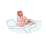 Woman in pink pajamas sits on a bed, hugging her knees with a worried expression beside a pillow and blanket.